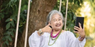 Elderly Woman Relaxing On A Swing While Using A Tablet In A Serene Outdoor Setting